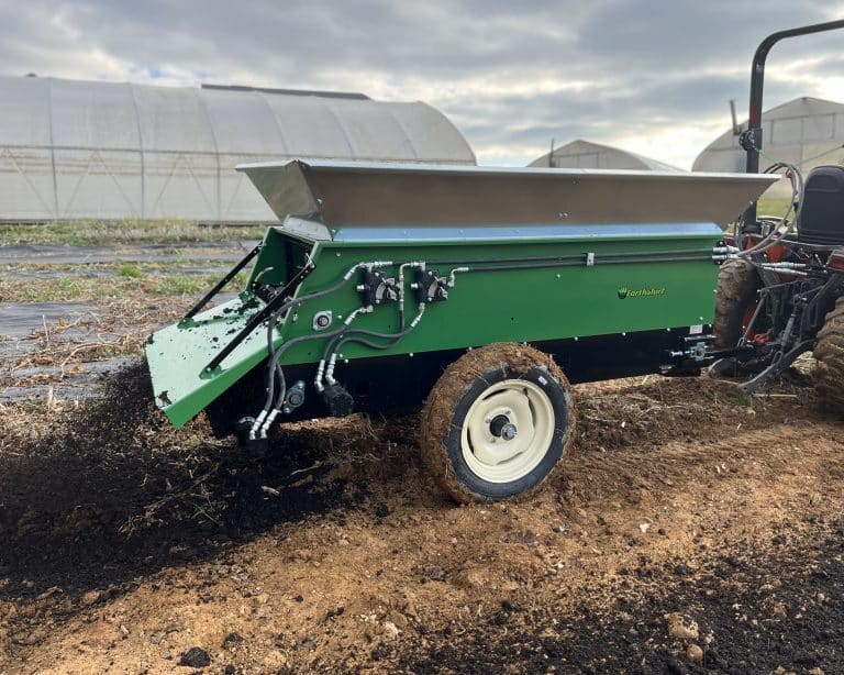 320 tow behind spreader spreading compost in a garden from earth and turf spreaders