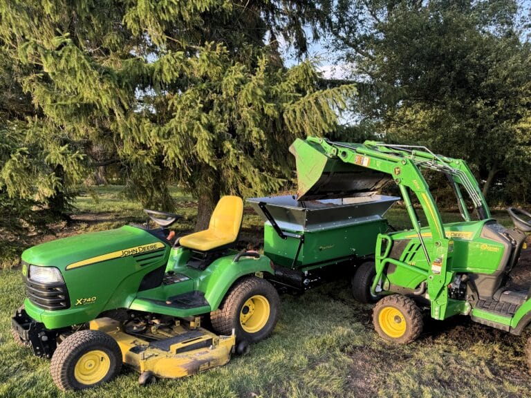 220 topdresser being pulled by a john deere lawn tractor. The topdresser has light material sides