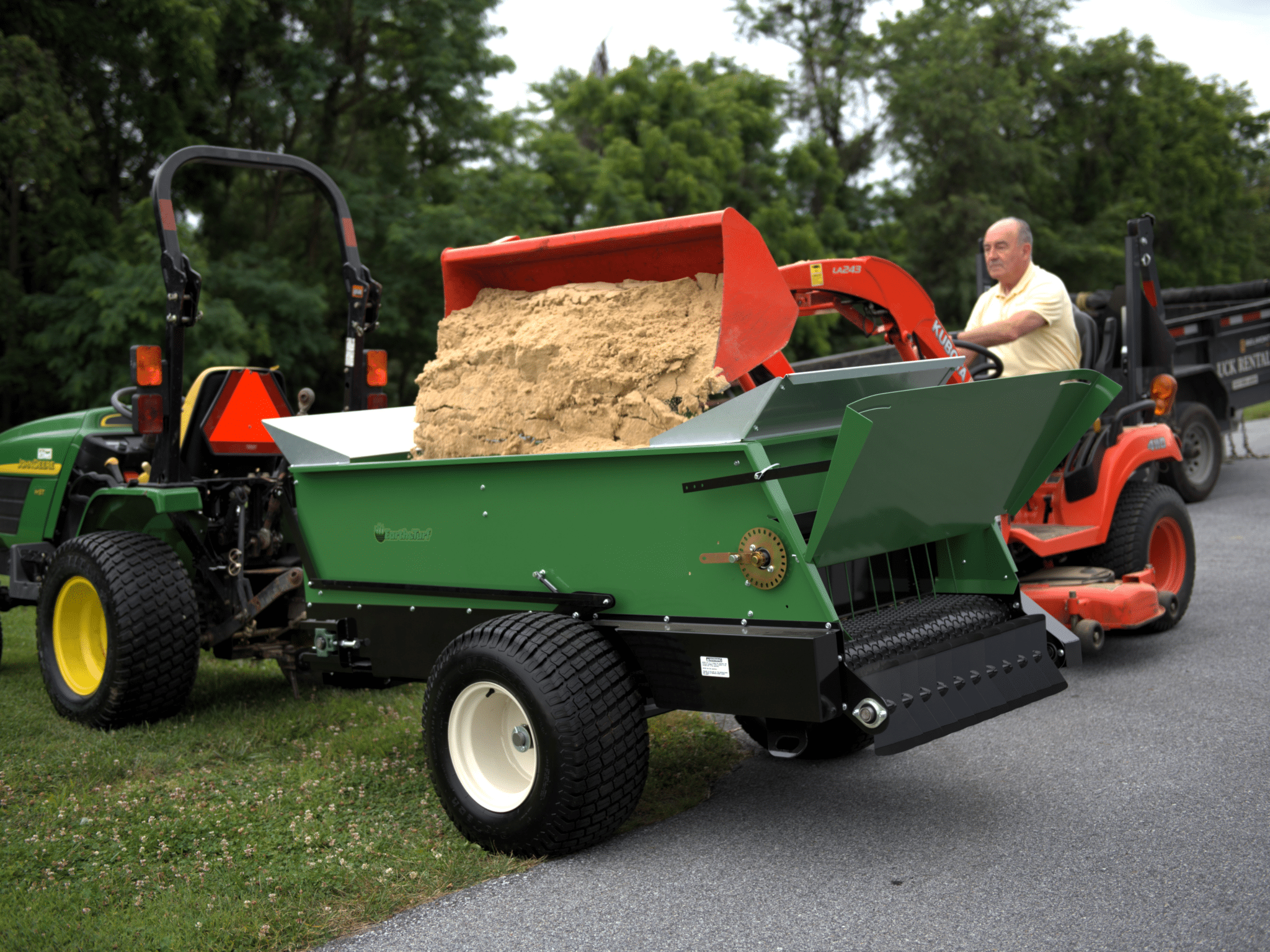 320 multispreader being loaded with sand by a tractor